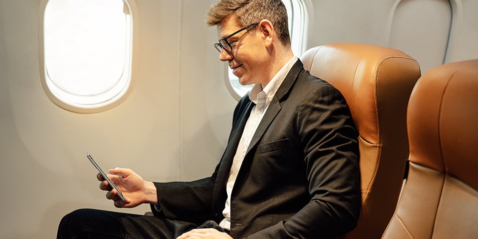 Businessman using smartphone while sitting in first class.