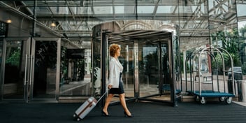 Businesswoman walking in front of luxury hotel with suitcase