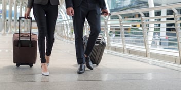 two business people with luggage in an airport
