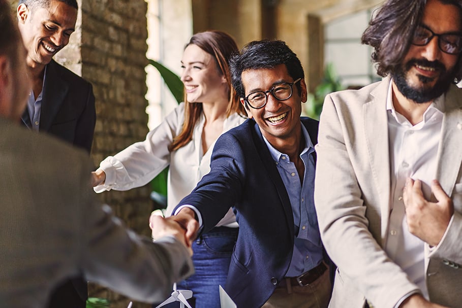 Business professionals smiling and shaking hands in a modern office setting