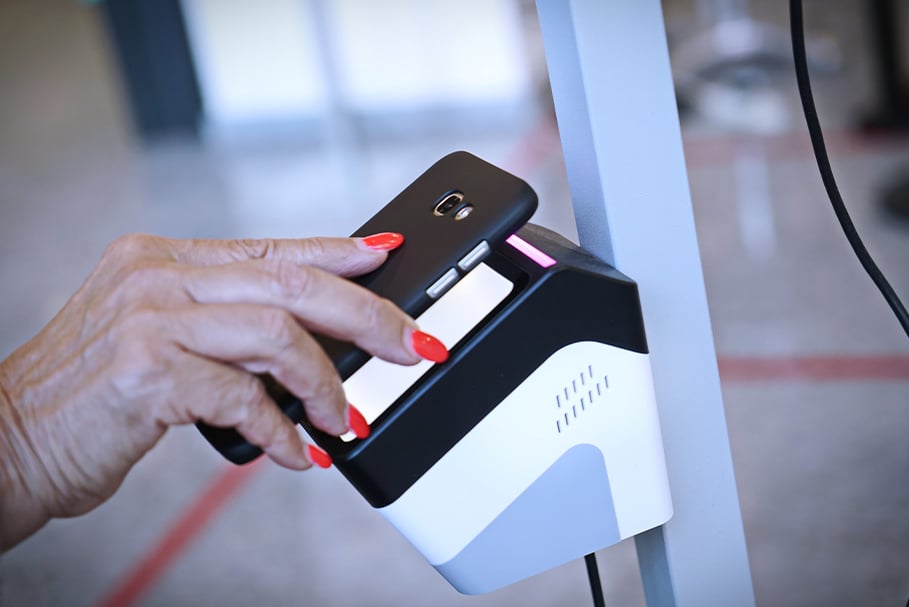 Hand with red nails using smartphone for contactless payment at terminal