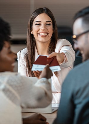 Smiling travel agent handing tickets to her clients.