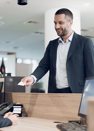 A businessman handing a card to a receptionist.