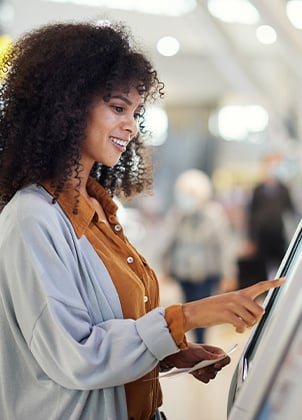 Female traveler by kiosk machine at an airport.