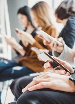 A group of people all using their smartphones in a public place