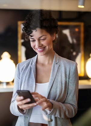 Young businesswoman standing inside a hotel lobby using mobile phone