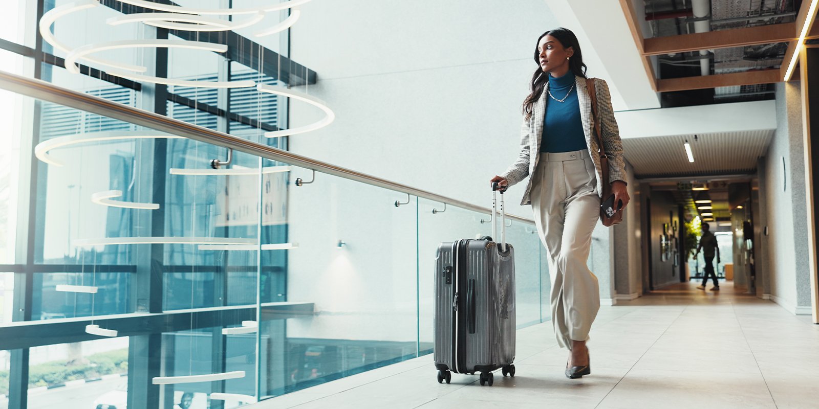 Businesswoman walking with her suitcase in an airport for business travel.