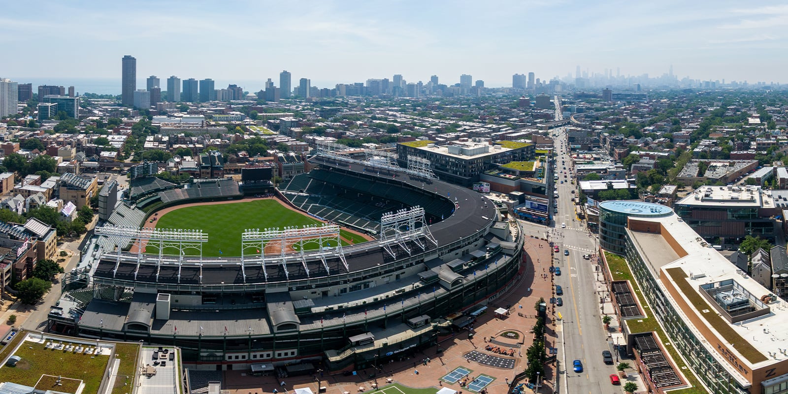 Aerial view of Wrigley Field in Chicago, with the city skyline and Lake Michigan visible in the background.