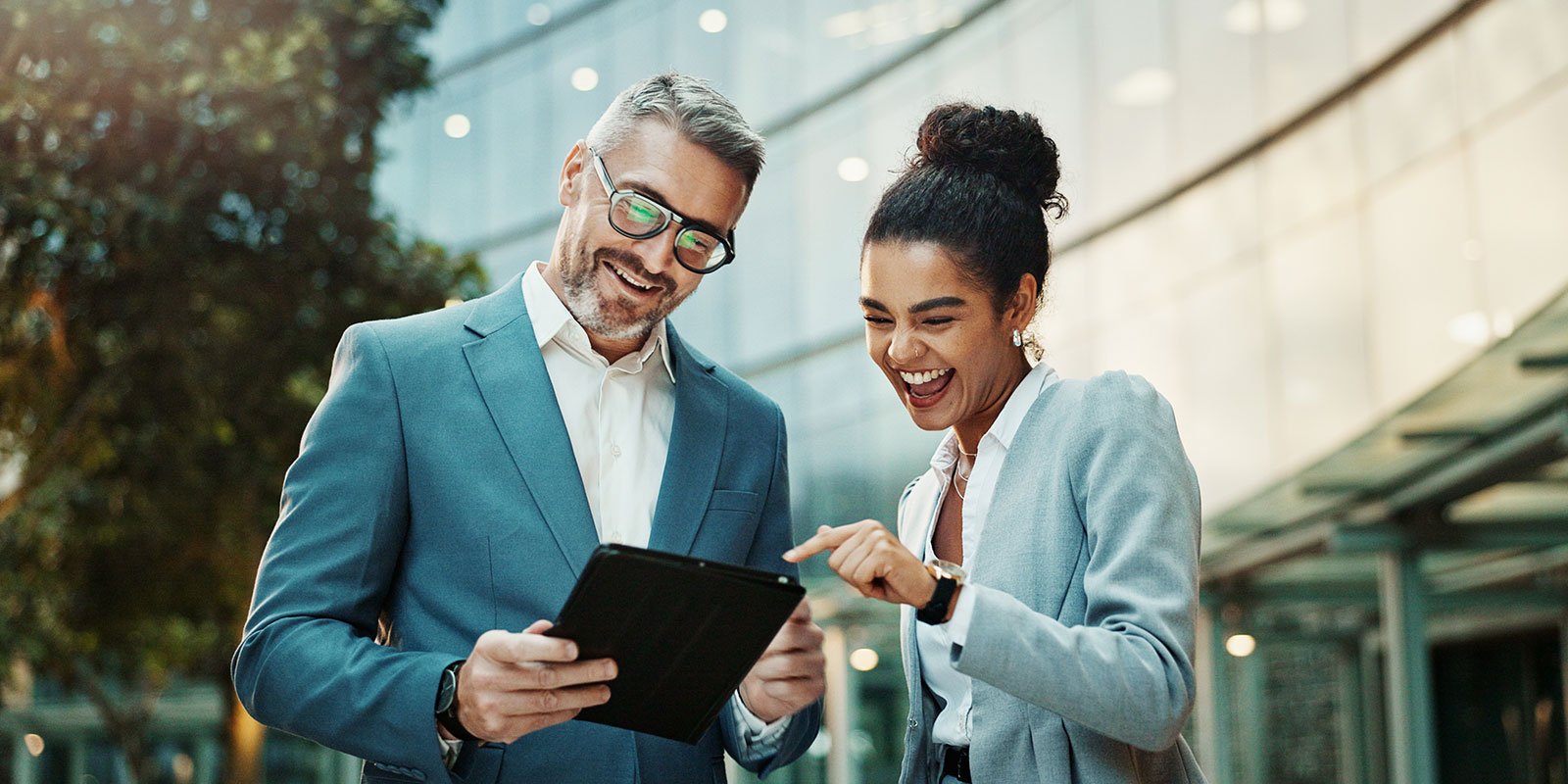 businessman and woman looking at tablet outside building